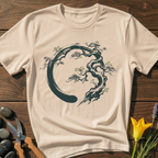 Beige t-shirt with tree design on a wooden surface with scissors and flowers.