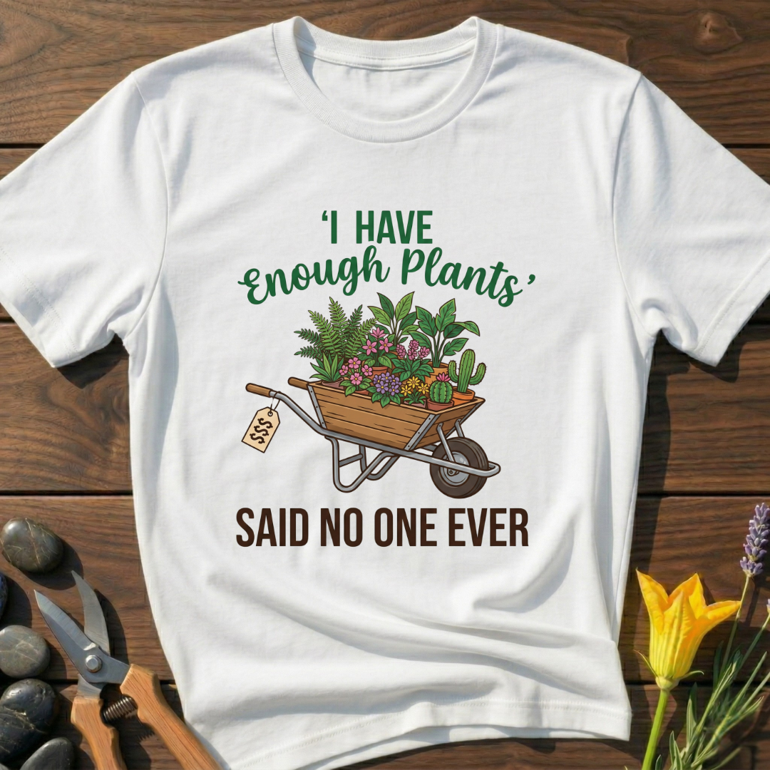 White t-shirt with gardening graphic and text on a wooden surface with gardening tools and flowers.